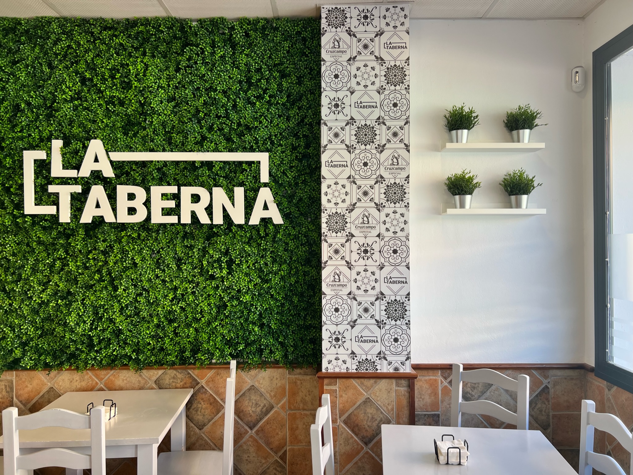 Interior del Bar La Taberna — ambiente acogedor con pared verde y azulejos